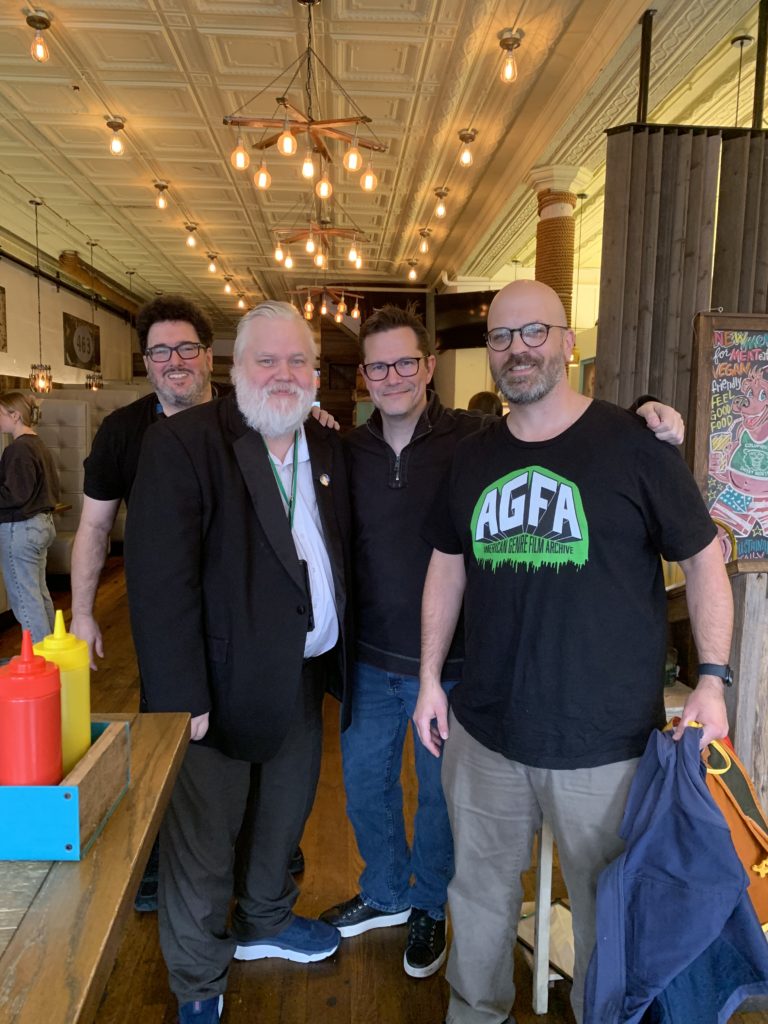 Mark A. Altman, Daren Dochterman, Ashley Miller, and Lucas Hardwick pose for a group photo in a restaurant.