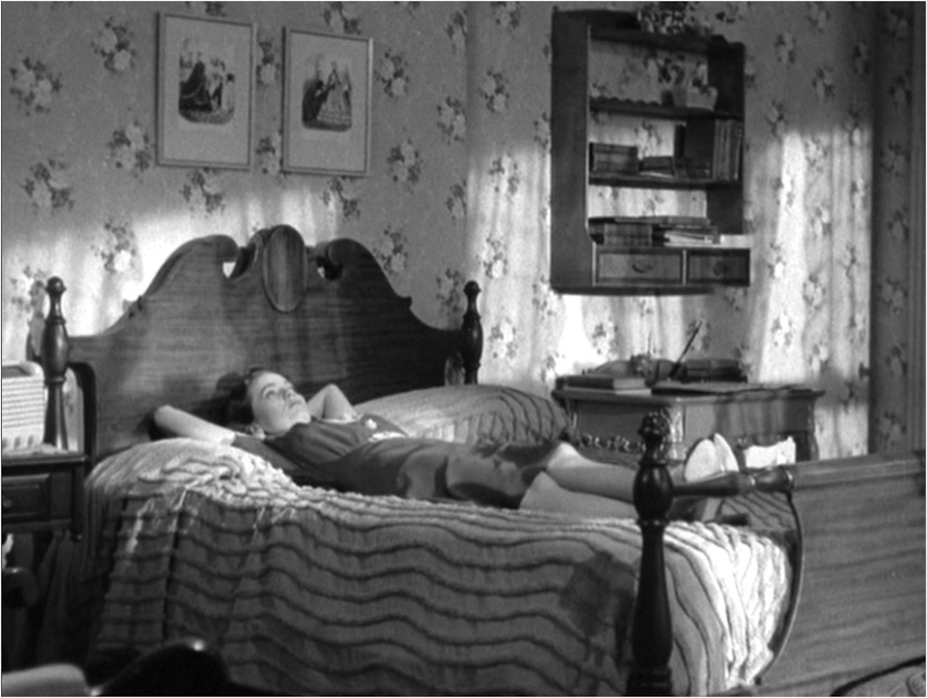 A frustrated young Charlie Newton, played by Teresa Wright, lying on the bed of her room; afternoon sunshine filters through the draped windows.