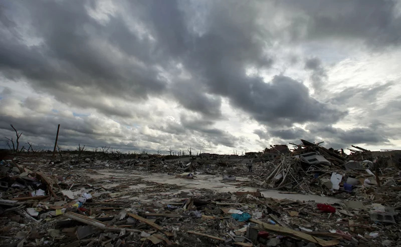 A wide shot of destroyed buildings and trees immediately after a tornado