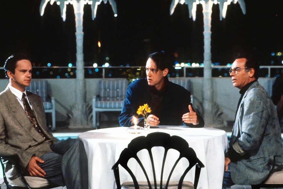 Griffin (Robbins) sitting at a restaurant table with Tom Oakley (Richard E. Grant) and a producer.