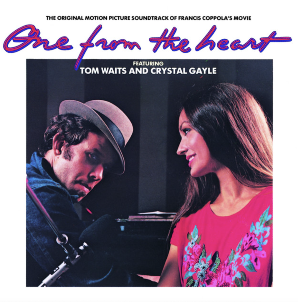 The album cover of the “One from the Heart” soundtrack, featuring Tom Waits sitting at a piano, looking at us and Crystal Gayle looking back at him