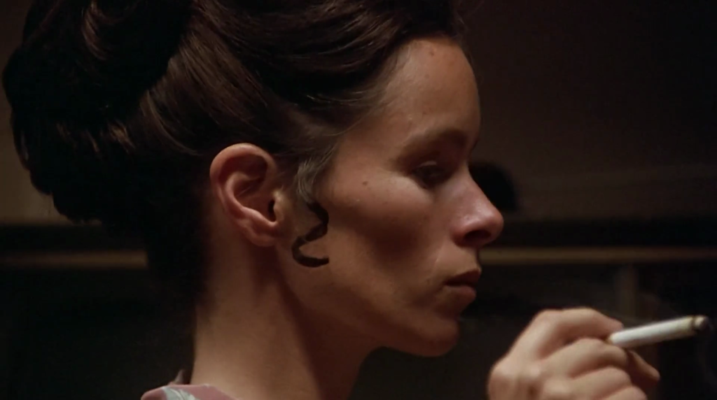 A close-up shot of Emily (Geraldine Chaplin) smoking a cigarette in Remember My Name.