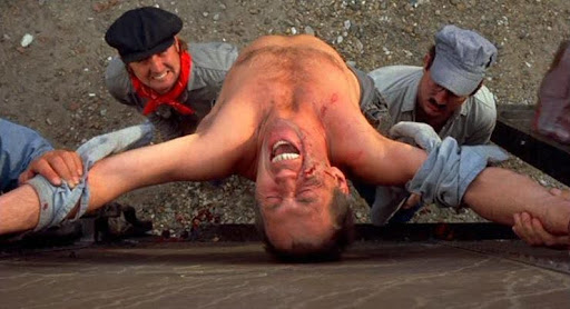 Bill Shelley (David Carradine), shirt torn, screaming in pain as railroad employees crucify him on the side of a train car, from Boxcar Bertha (1972).