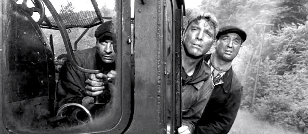 black-and-white image of three white men behind the window of a train