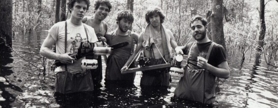 Five men stand waist deep in water with film equipment