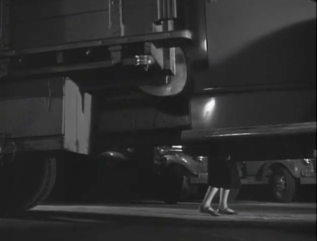 A woman’s legs are visible under the body of a truck. 