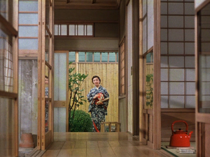 Ozu’s color film Equinox Flower demonstrates his love of the color red, as in this frame which shows a woman carrying a red teapot into a building.