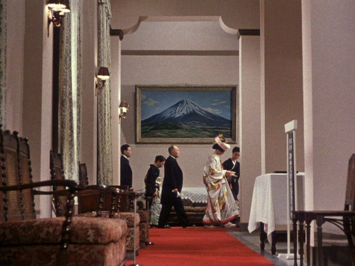 A shot from an early wedding sequence in Ozu’s Equinox Flower, with the color of the carpet exemplifying the director’s interest in the color red.