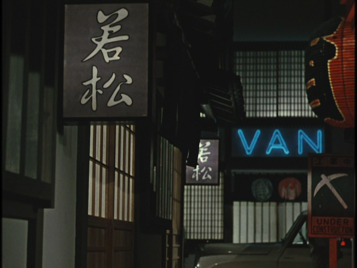 This frame shows Ozu’s playful use of color in a shot from outside a restaurant; with red lanterns peeking out from the side of the frame and a neon blue sign in the back reading "VAN".