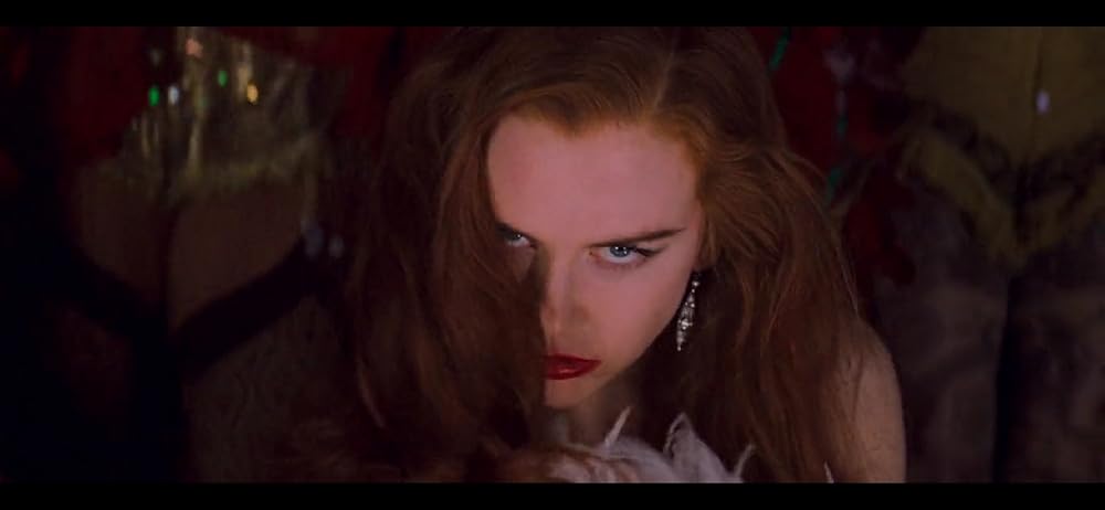 Nicole Kidman, as Satine, a light-skinned woman with loose ginger hair, is gazing at the camera with a look of dangerous seduction on her face.