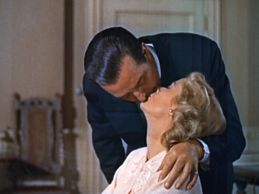 A husband and wife kiss at the breakfast table