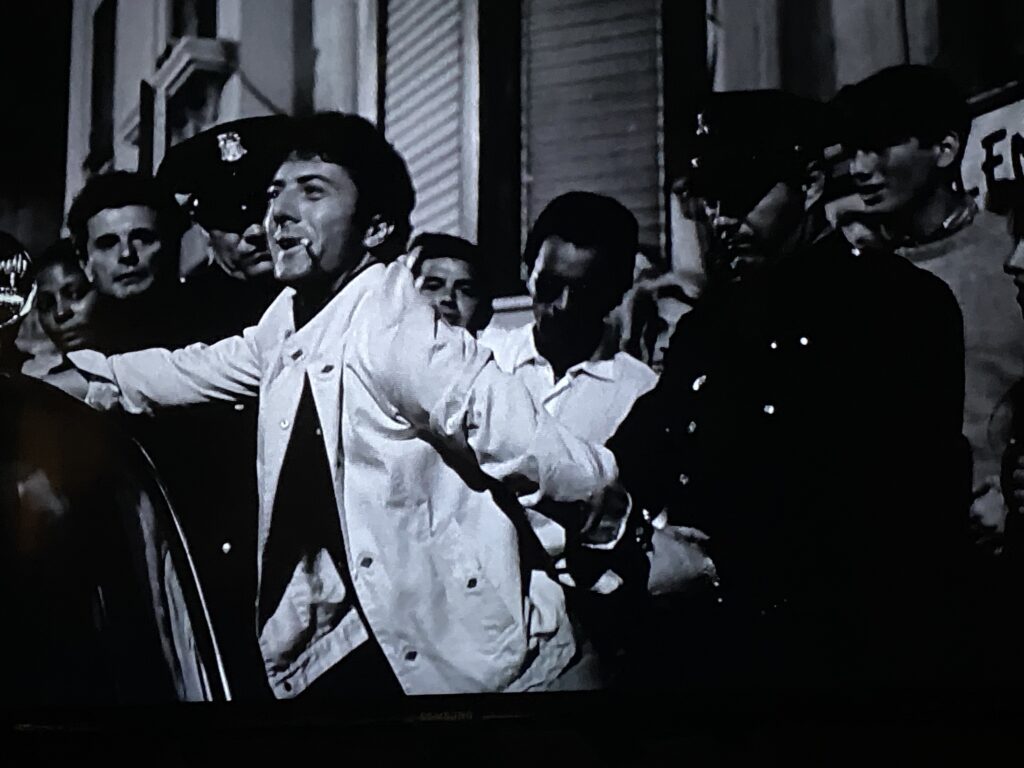 Black and white image of Lenny Bruce being arrested outside a club.