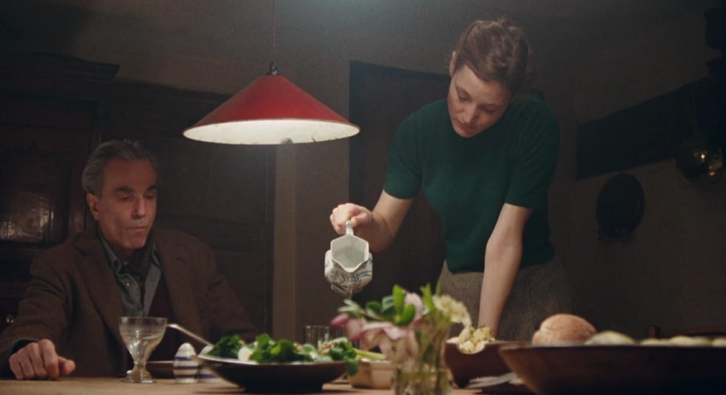 Alma and Reynolds at the dinner table; Alma pours him water.